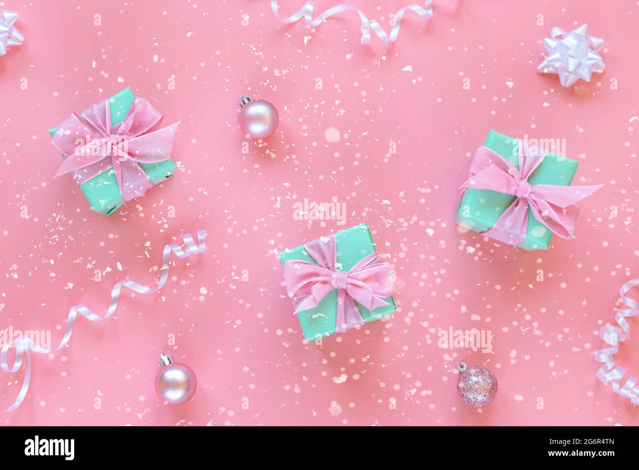 Trois boîtes cadeau vertes avec noeud sur fond rose avec des doubles-bbles et des confettis. Concept de Noël. Vue de dessus, plan d'appartement Banque D'Images