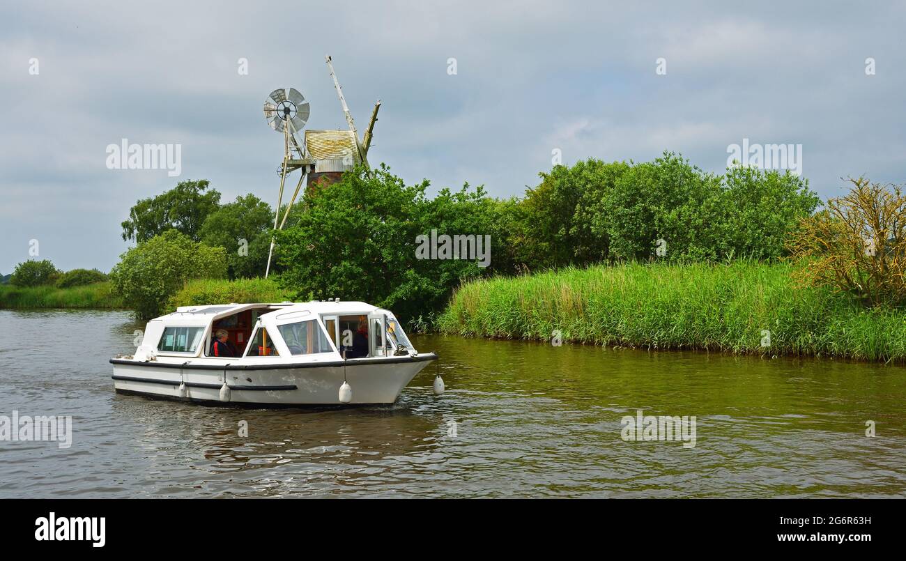 Broads Cruiser sur la rivière Ant à How Hill Norfolk avec moulin à vent - pompe à vent en arrière-plan. Banque D'Images