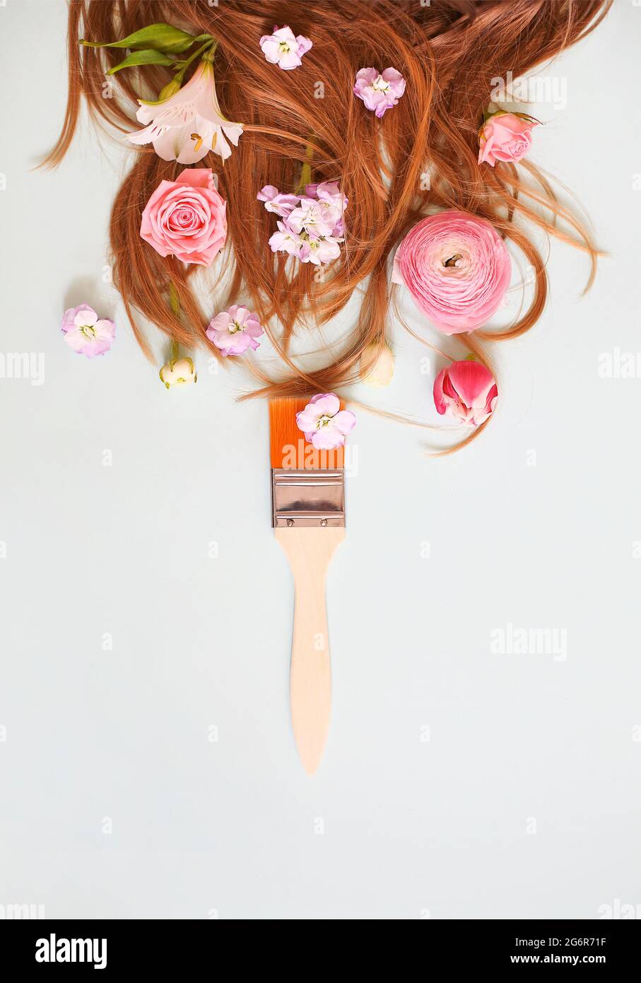 Vue de dessus du pinceau et des fleurs délicates placées près de longs cheveux de gingembre de la femme sur fond gris Banque D'Images