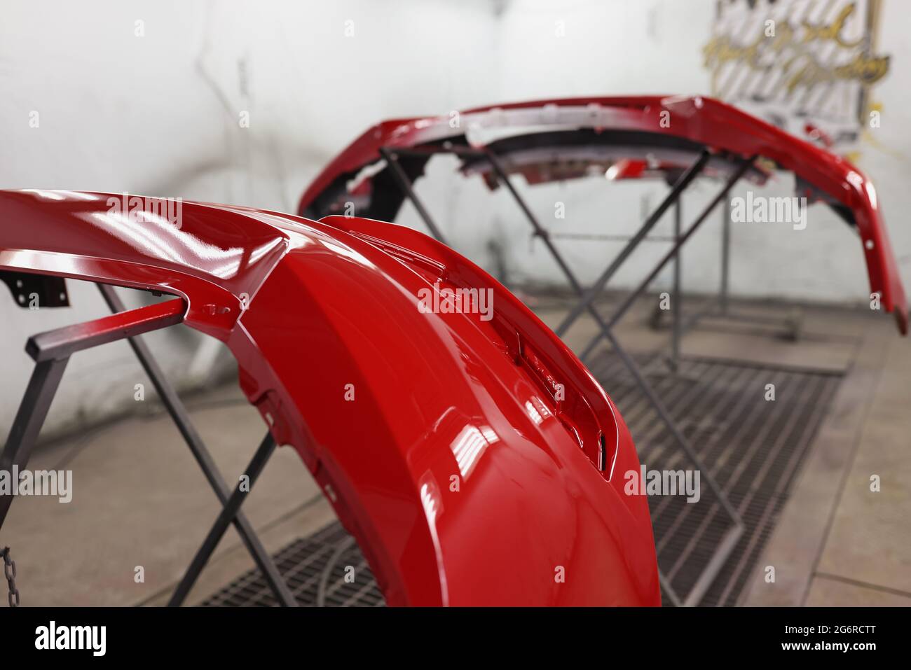 Le pare-chocs de voiture en plastique rouge se desséchant après peinture dans la cabine de pulvérisation Banque D'Images