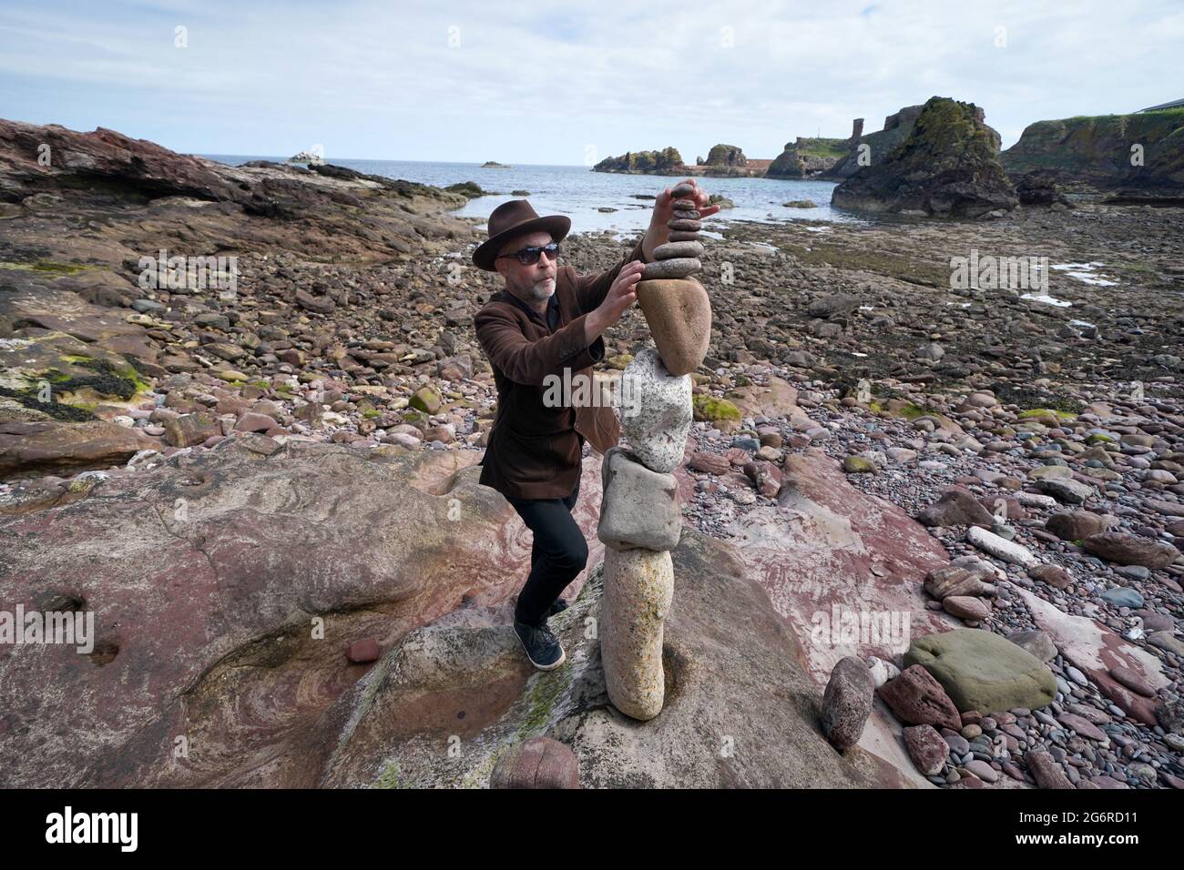 L'artiste James Craig page empile des pierres avec ses créations de sculptures en pierre sur la plage Eye Cave à Dunbar, Lothian est, devant les championnats européens de superposition de pierres. Les amateurs, les familles et les papillotes de pierre professionnels participeront à divers défis le samedi et le dimanche. Date de la photo: Jeudi 8 juillet 2021. Banque D'Images