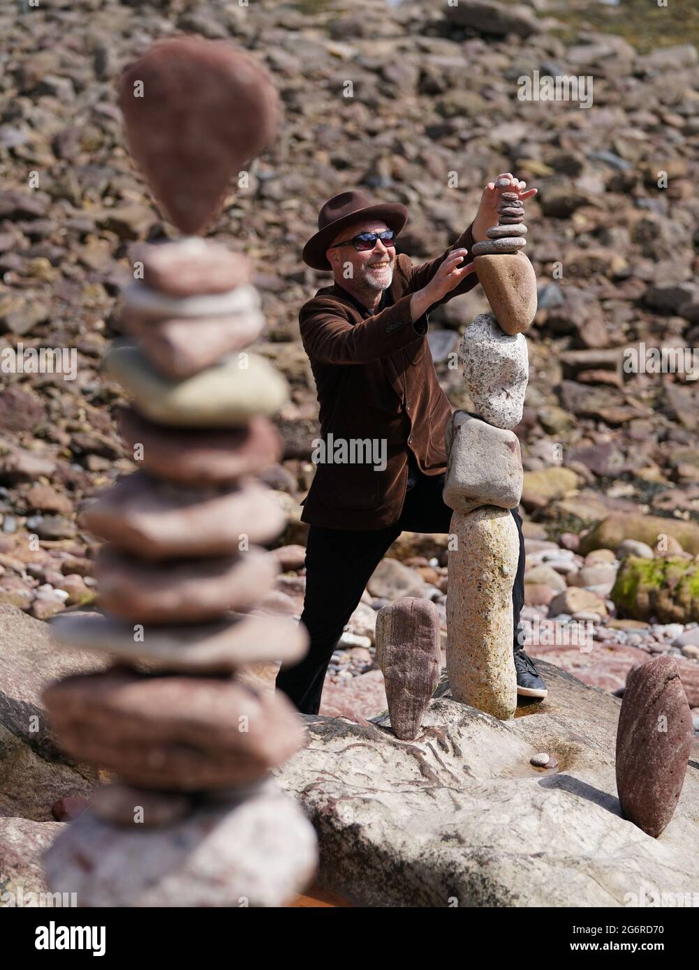 L'artiste James Craig page empile des pierres avec ses créations de sculptures en pierre sur la plage Eye Cave à Dunbar, Lothian est, devant les championnats européens de superposition de pierres. Les amateurs, les familles et les papillotes de pierre professionnels participeront à divers défis le samedi et le dimanche. Date de la photo: Jeudi 8 juillet 2021. Banque D'Images