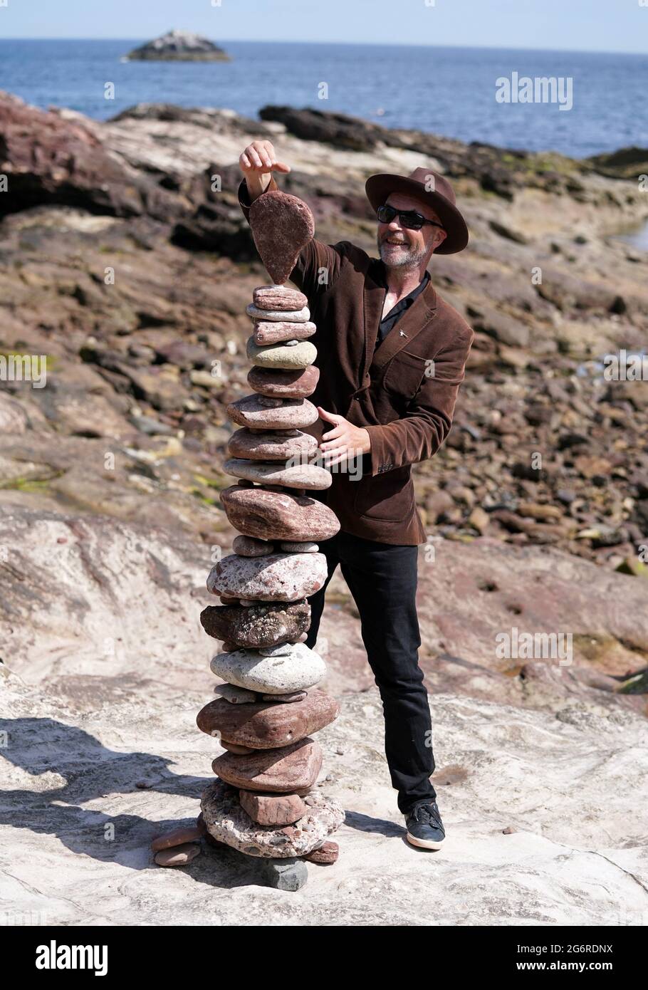 L'artiste James Craig page empile des pierres avec ses créations de sculptures en pierre sur la plage Eye Cave à Dunbar, Lothian est, devant les championnats européens de superposition de pierres. Les amateurs, les familles et les papillotes de pierre professionnels participeront à divers défis le samedi et le dimanche. Date de la photo: Jeudi 8 juillet 2021. Banque D'Images