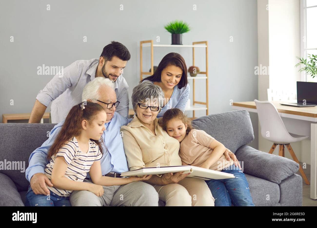Une famille heureuse assise sur un canapé, lisant un livre ou regardant ensemble un album photo Banque D'Images