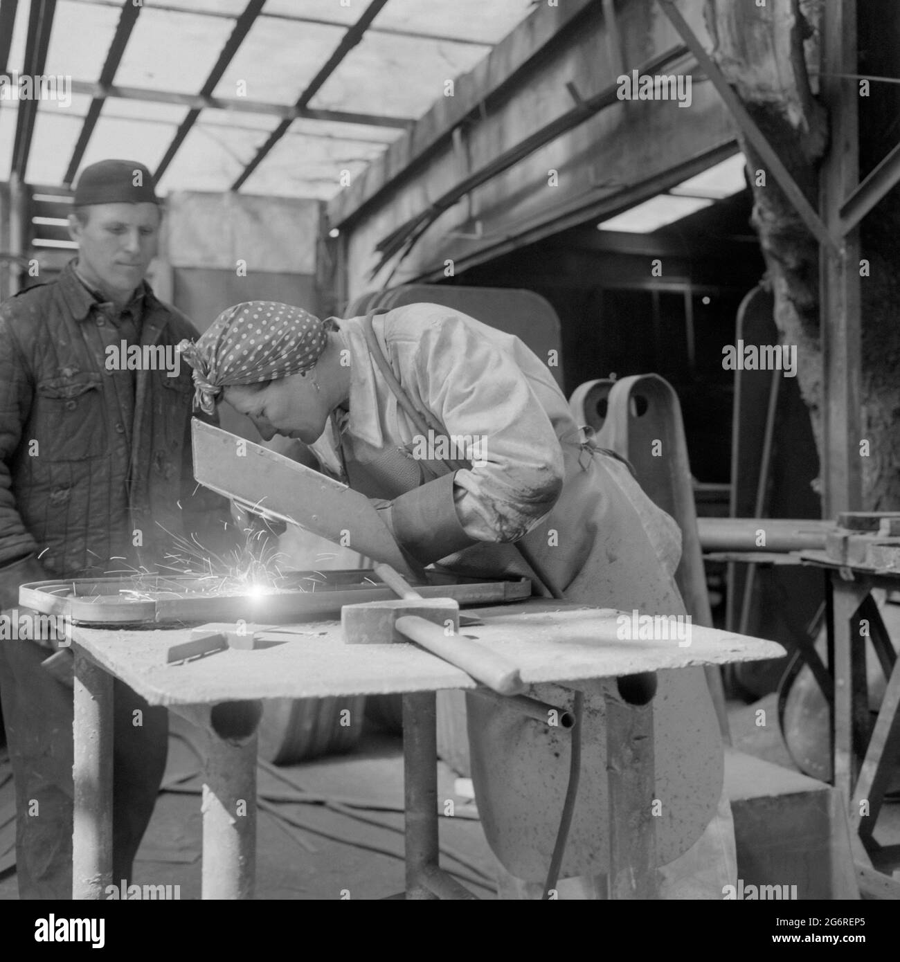 femme soudant tandis que collègue de travail de sexe masculin regarde sur le chantier naval années 1960 budapest hongrie Banque D'Images