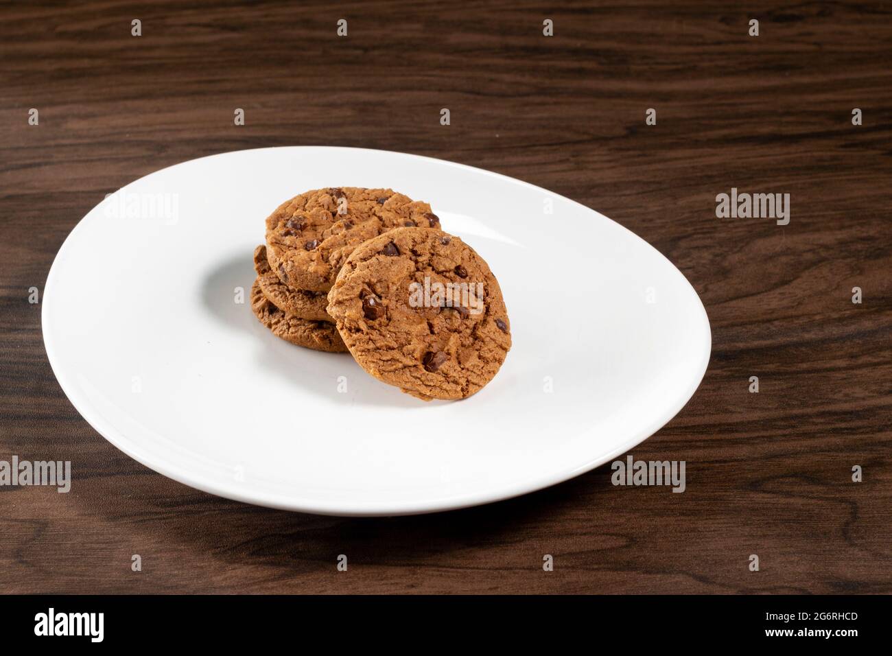 Assiette de biscuits aux pépites de chocolat fraîchement cuites. Arrière-plan en bois, mise au point sélective Banque D'Images