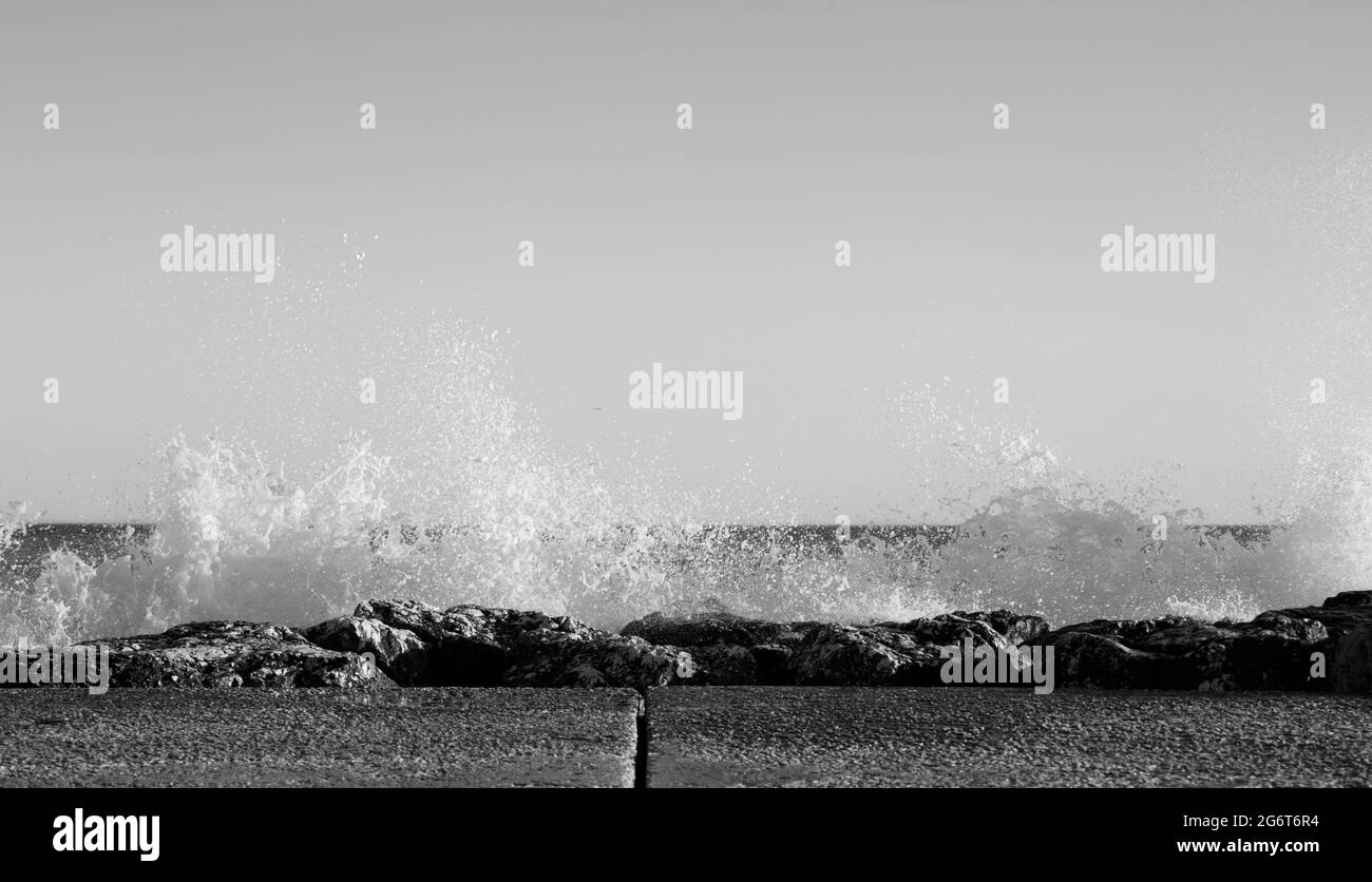 Des vagues éclaboussés sur des rochers lors d'une journée très venteuse au coucher du soleil (heure d'or). Banque D'Images