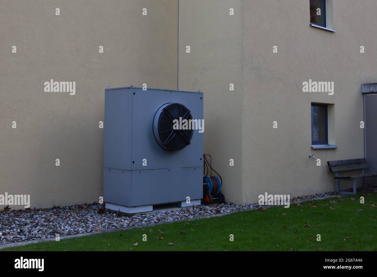 Pompe à chaleur de la source d'air de couleur grise installée à l'extérieur de la maison peinte en jaune pastel pour le chauffage et la climatisation des maisons. Ils fonctionnent en déplaçant la chaleur. Banque D'Images