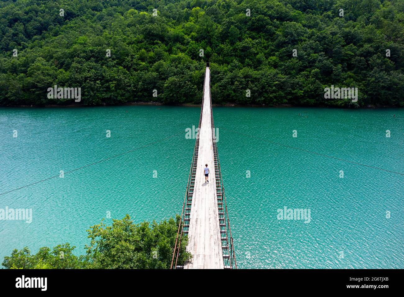 Garçon marchant sur un pont suspendu ou suspendu au-dessus de la belle rivière émeraude, Albanie Banque D'Images