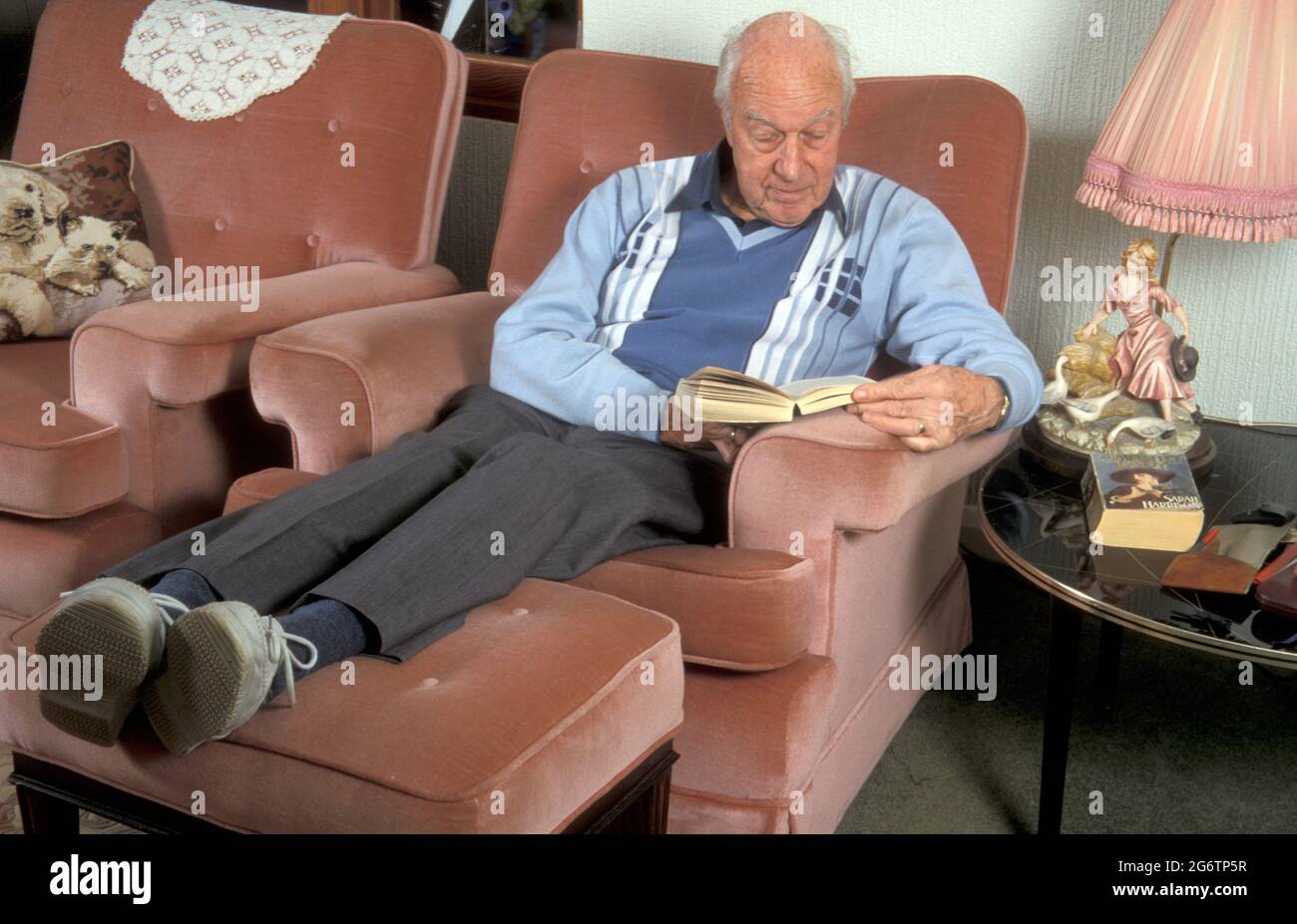 homme âgé en fauteuil inclinable lisant un livre Banque D'Images