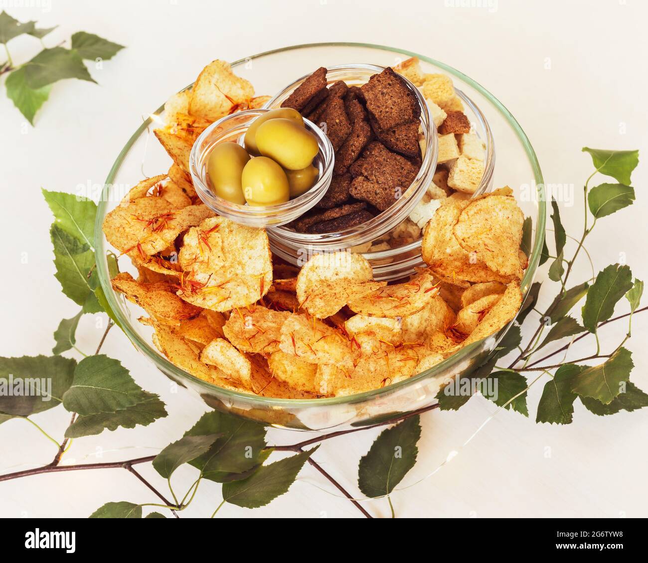 Été, composition alimentaire avec bière, encas solty : crackers de seigle, crackers de blé, chips de pomme de terre avec épices et olives vertes dans des bols en verre Banque D'Images