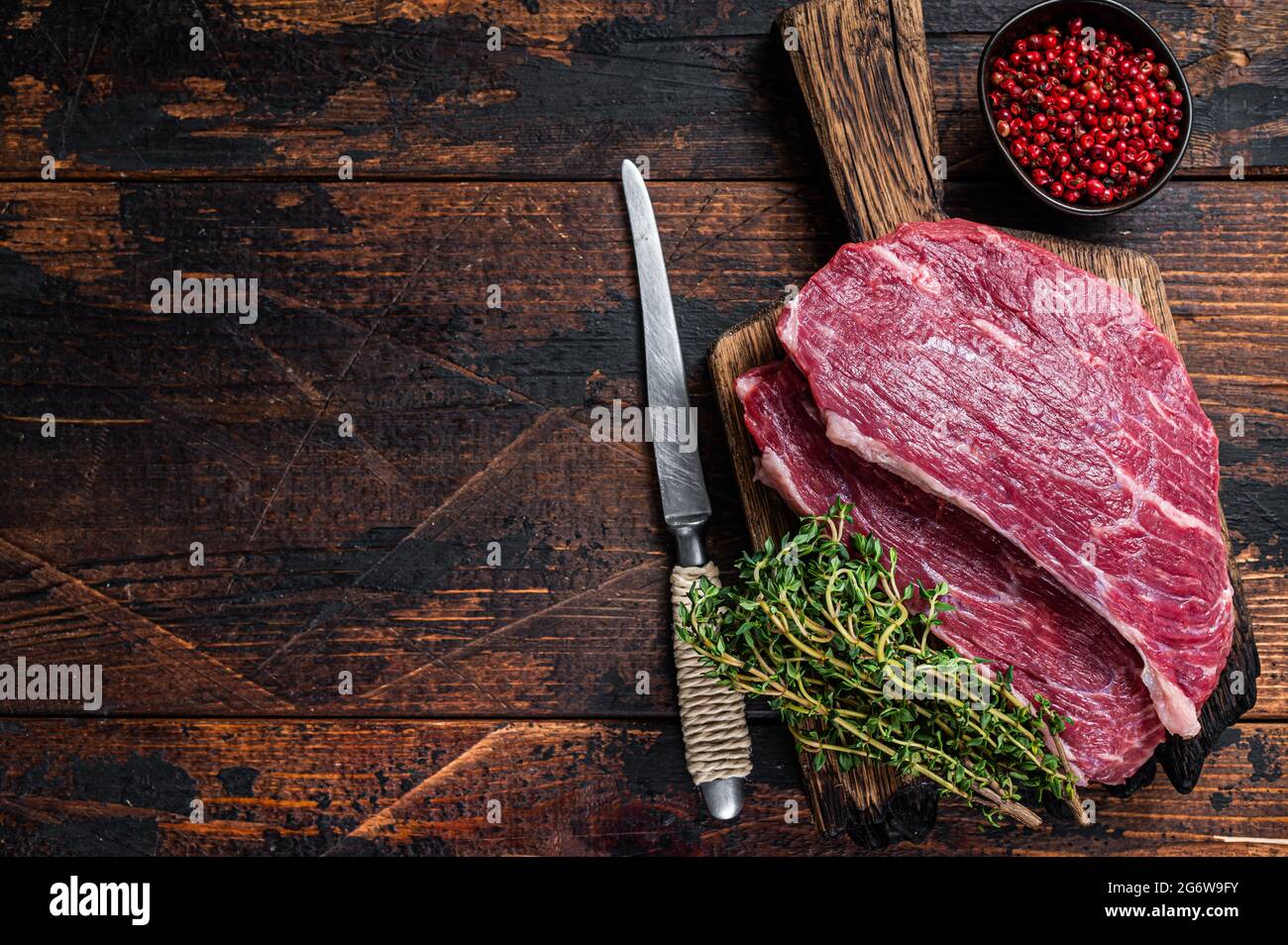 Steak de chapeau de sirloin cru ou steak de Picanha sur une planche de bois au thym. Arrière-plan en bois sombre. Vue de dessus. Copier l'espace Banque D'Images