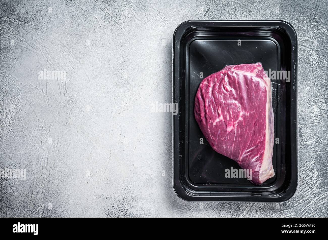 Steak de bœuf cru ou steak de viande de bœuf au sirloin dans un emballage sous vide. Arrière-plan blanc. Vue de dessus. Copier l'espace Banque D'Images