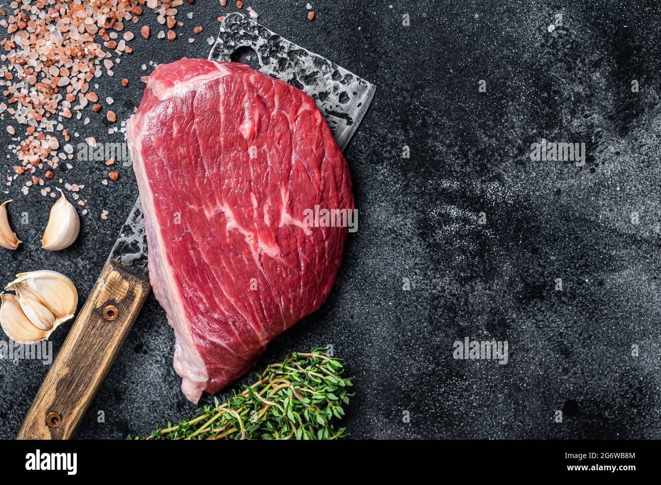 Bœuf cru frais coupé ou steak de chapeau de sirloin sur le couperet de boucher. Arrière-plan noir. Vue de dessus. Copier l'espace Banque D'Images