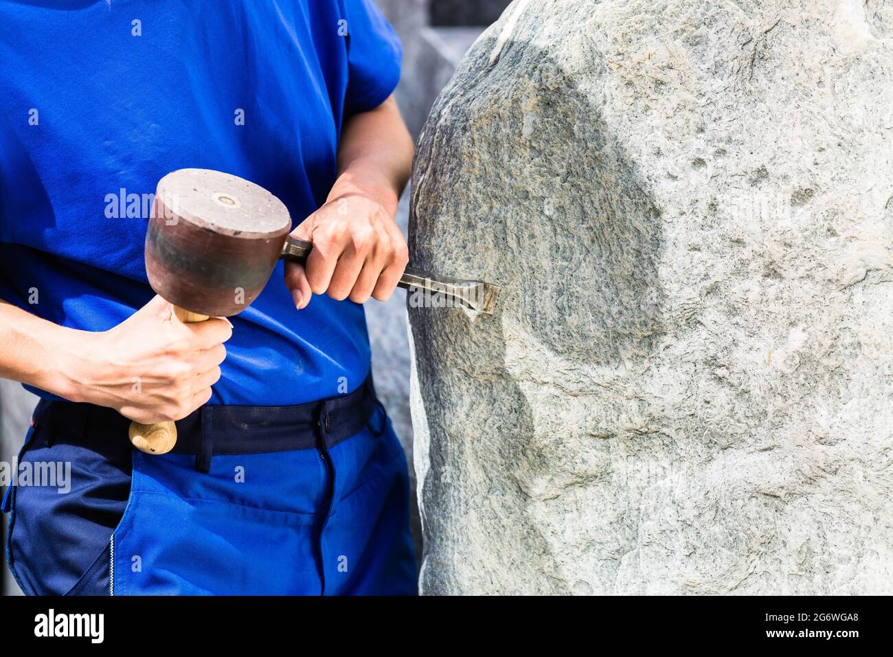 Travail de pierre sur le rocher avec marteau de traîneau et fer en atelier Banque D'Images