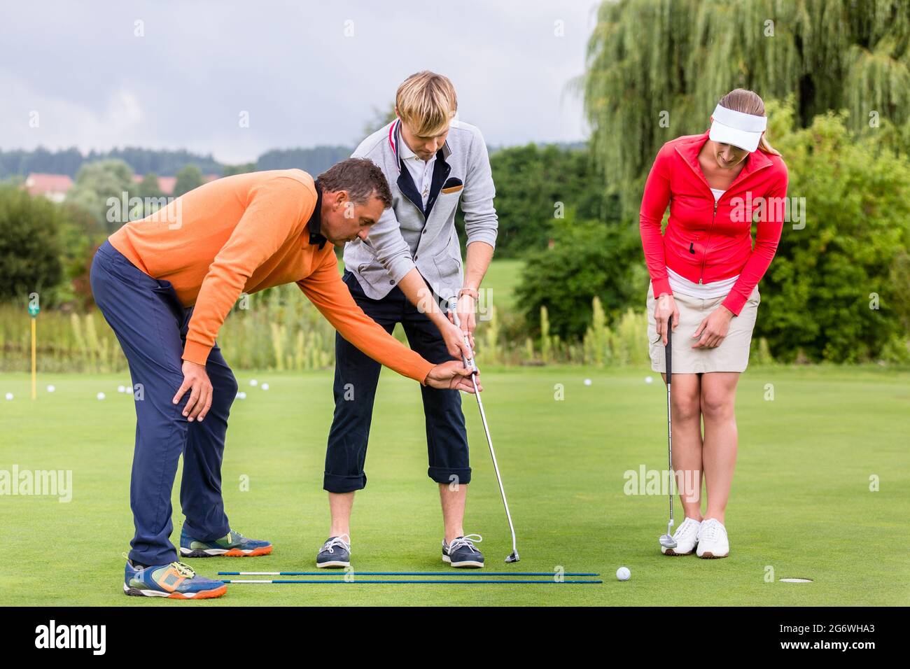 Entraîneur de golf mâle mature enseignant au couple de jouer au golf sur le terrain Banque D'Images