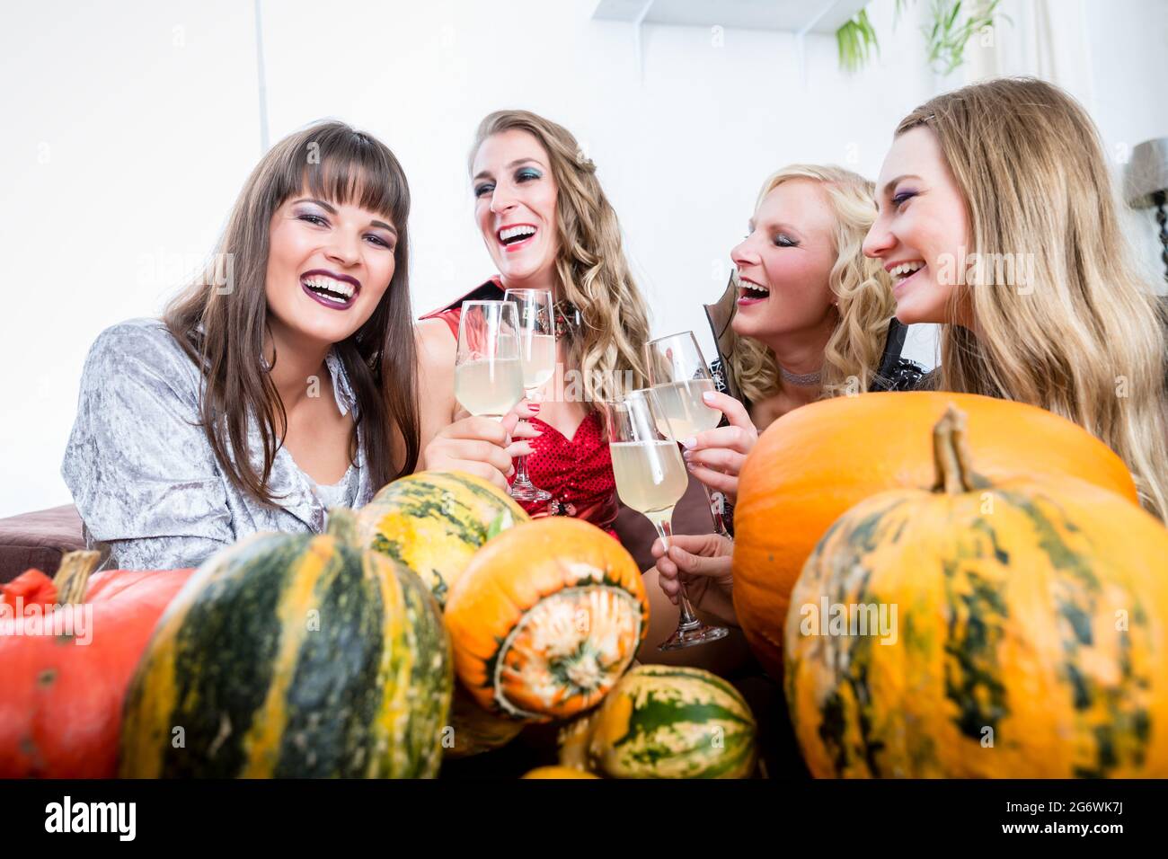 Jeune et belle femme posant drôle et effrayant tout en toasting avec ses meilleurs amis pendant la fête de costume d'Halloween Banque D'Images