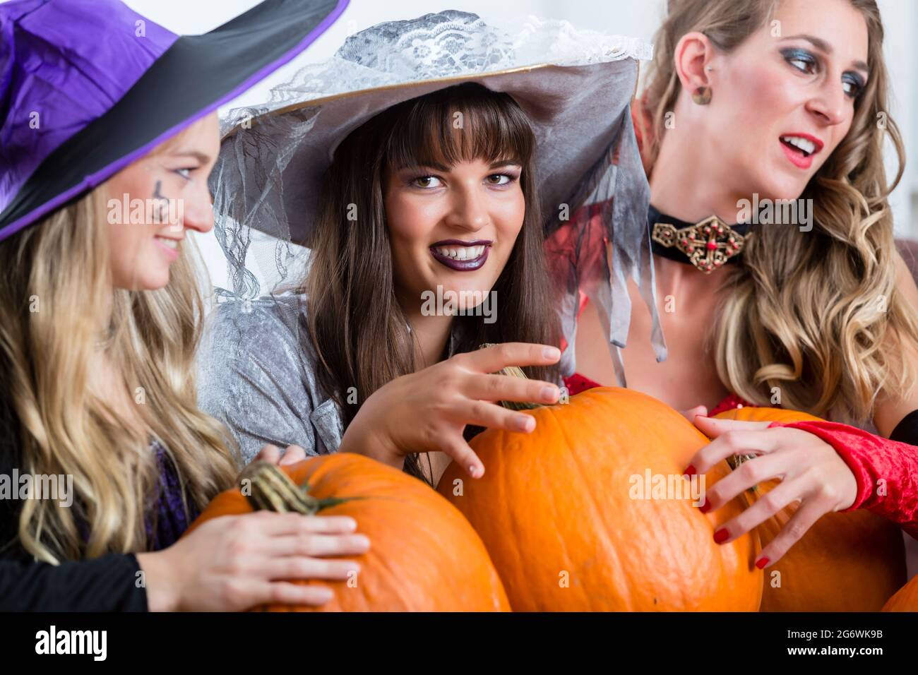 Trois jeunes et belles femmes portant des costumes bon marché tout en agissant comme des sorcières se joindre à leurs forces malveillantes à l'Halloween Banque D'Images