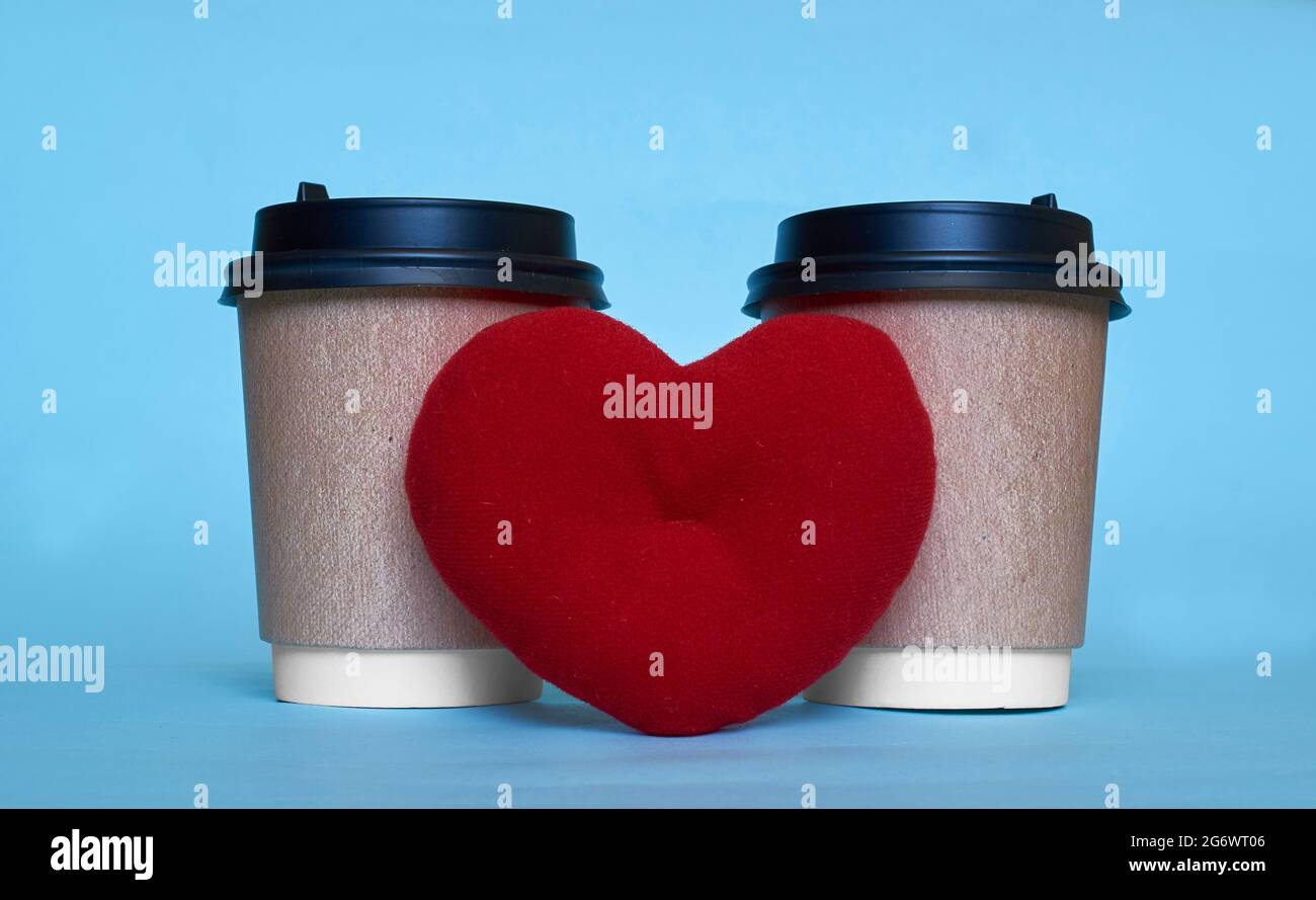 Deux tasses en papier pour le café et un coeur jouet.Espace pour le texte Banque D'Images