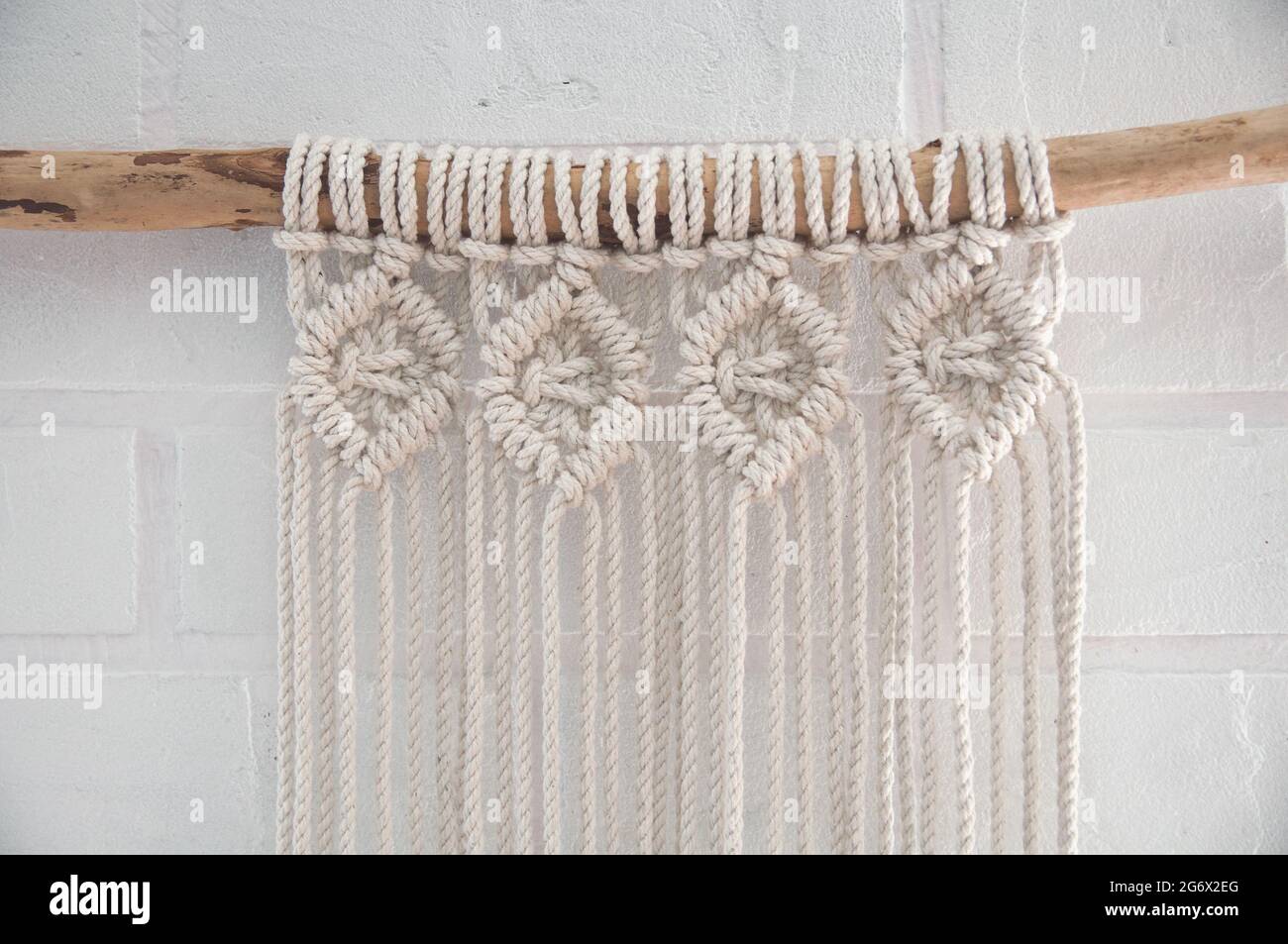 Murale boho en fils de coton de couleur naturelle utilisant la technique du macrame pour la décoration de la maison et du mariage Banque D'Images
