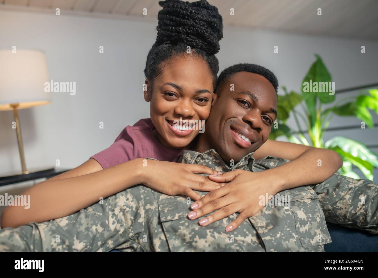 Femme brillante embrassant l'homme en uniforme militaire Banque D'Images