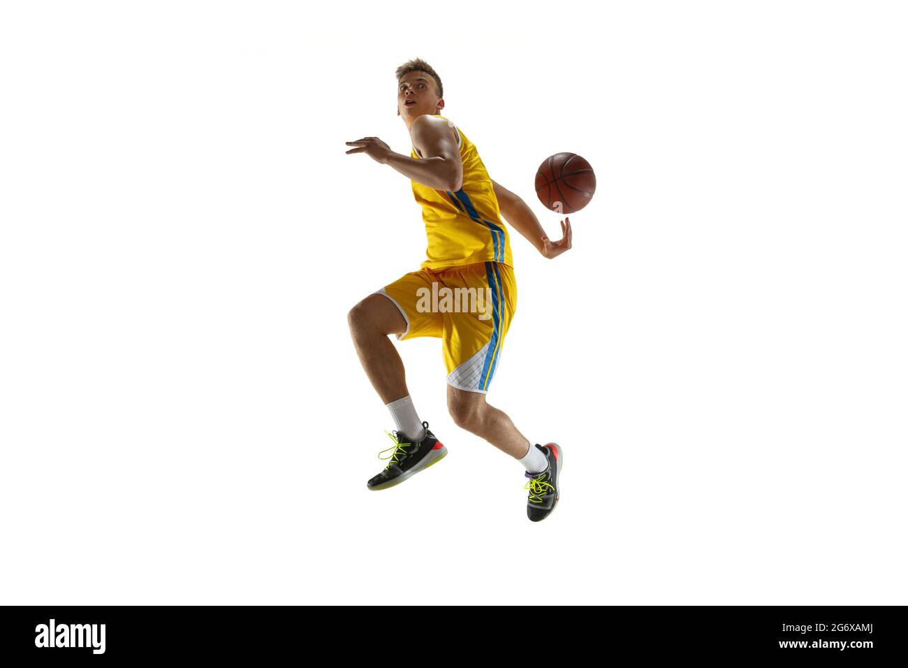 Vue latérale. Un jeune homme, joueur de basket-ball avec un entraînement de balle isolé sur fond blanc studio. Concept publicitaire. Athlète caucasien en action Banque D'Images