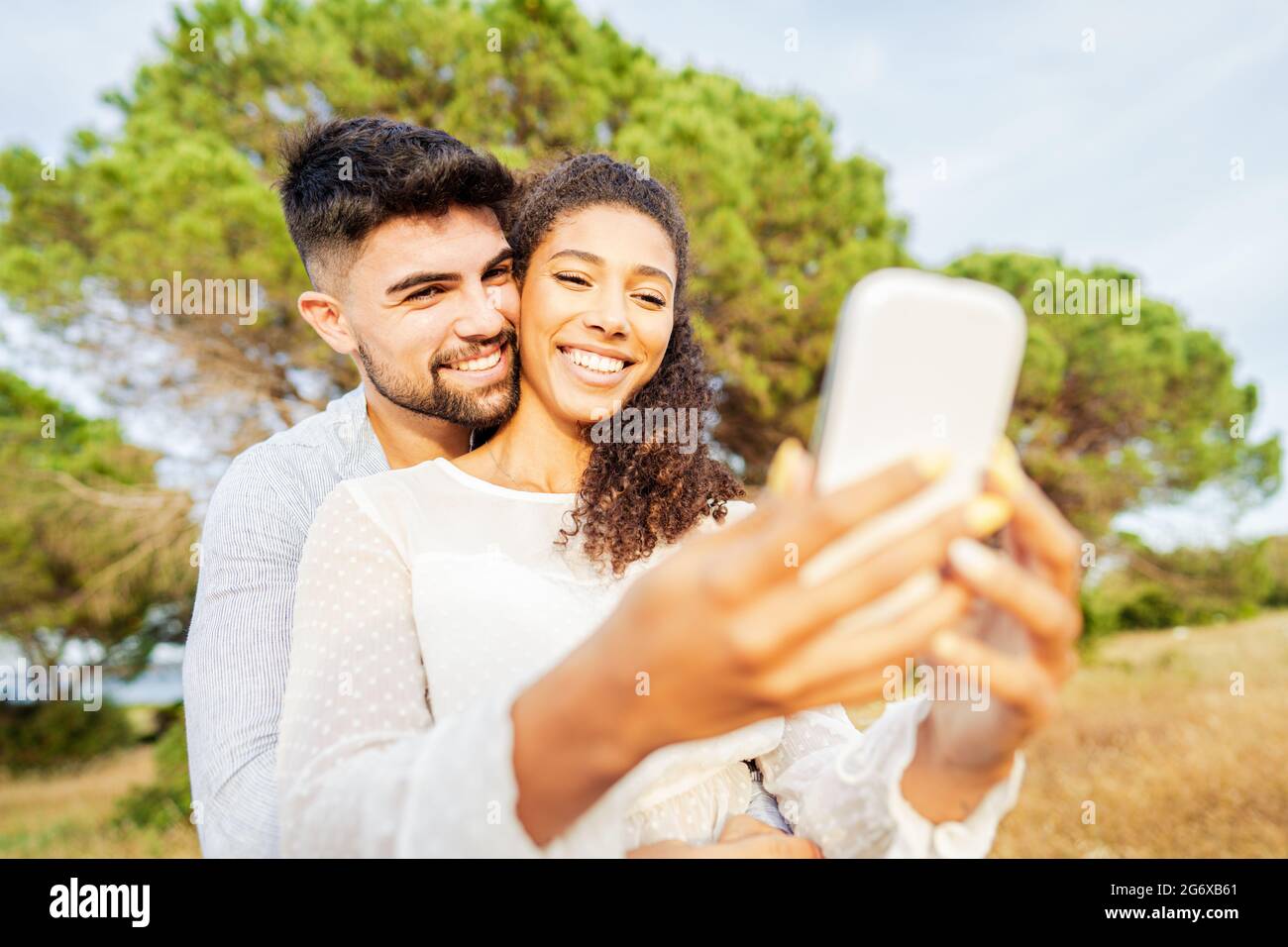 Jeune beau couple multiracial amoureux de prendre selfie dans la nature appréciant des vacances partager des photos sur les réseaux sociaux. Nouvelle technologie normale Banque D'Images