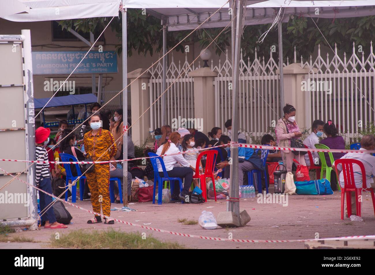 Phnom Penh, Cambodge. 9 juillet 2021. Pendant 4 mois, Phnom Penh a lutté contre une augmentation de la COVID - 19. Les Cambodgiens, dans des masques protecteurs / couvertures, qui ont testé positif pour le virus attendent les ambulances, avec leurs sacs emballés, à un site d'essai de masse. Une mère cambodgienne attend avec sa fille, ils ont tous deux été testés positifs. Les Cambodgiens qui ont obtenu un test positif ne peuvent pas quitter le site d'examen et doivent appeler un ami ou un parent pour récupérer leurs effets personnels pendant leur séjour de 2 semaines à l'hôpital. Crédit : Kraig Lieb / Alay Live News Banque D'Images