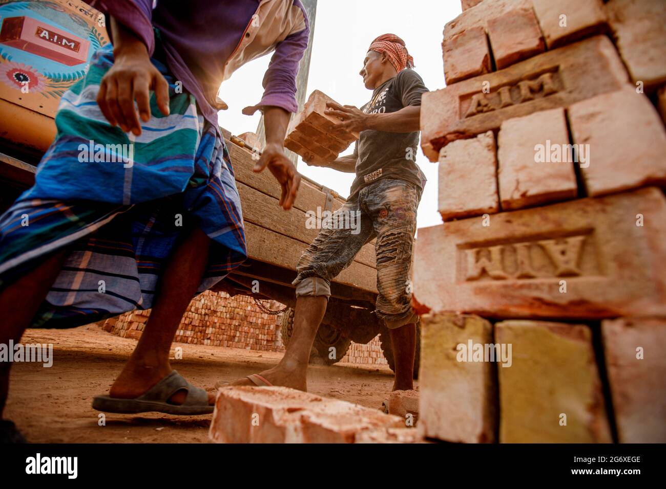 Les employés des fours à briques d'Ahulia empilent des briques fraîchement fabriquées sur des camions pour les expédier vers des sites de construction à Dhaka.en raison de la forte demande de matériaux de construction bon marché, la fabrication de briques en argile est devenue une industrie florissante au Bangladesh, avec des fours de fabrication fortement concentrés dans les périphéries de grandes villes. Ces sites de fabrication, connus sous le nom de brickfields, fonctionnent à l'aide de technologies vieilles de plusieurs siècles qui expulsent la poussière, les cendres, la fumée noire et d'autres polluants dans l'atmosphère Banque D'Images