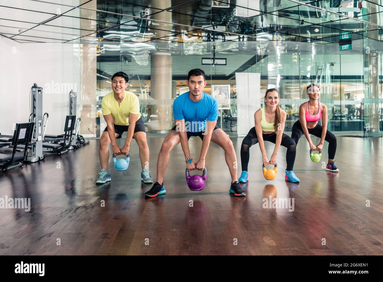 Sur toute la longueur de quatre jeunes gens joyeux et fit sourire tout en maintenant une classe de groupe lors de kettlebells entraînement fonctionnel dans la salle de sport Banque D'Images