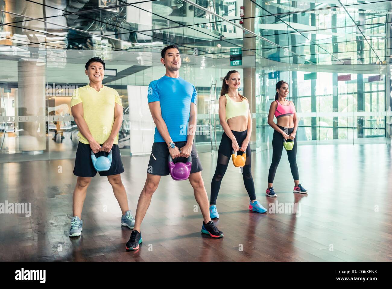 Sur toute la longueur de quatre jeunes gens joyeux et fit sourire tout en maintenant une classe de groupe lors de kettlebells entraînement fonctionnel dans la salle de sport Banque D'Images