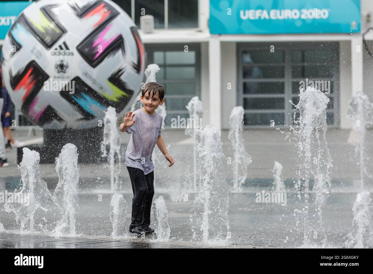 Wembley Park, Royaume-Uni. 9 juillet 2021. Les enfants jouent dans les fontaines devant le SSE Arena, où une réplique géante Adidas 'UNIFORIA FINALE' football - le ballon de match officiel pour les finales - est exposée sur Arena Square. 60,000 fans sont sur le point de descendre à Wembley Park pour regarder l'Angleterre jouer en Italie lors des finales de l'UEFA EURO 2020 au stade de Wembley le dimanche 11 juillet. Amanda Rose/Alamy Live News Banque D'Images