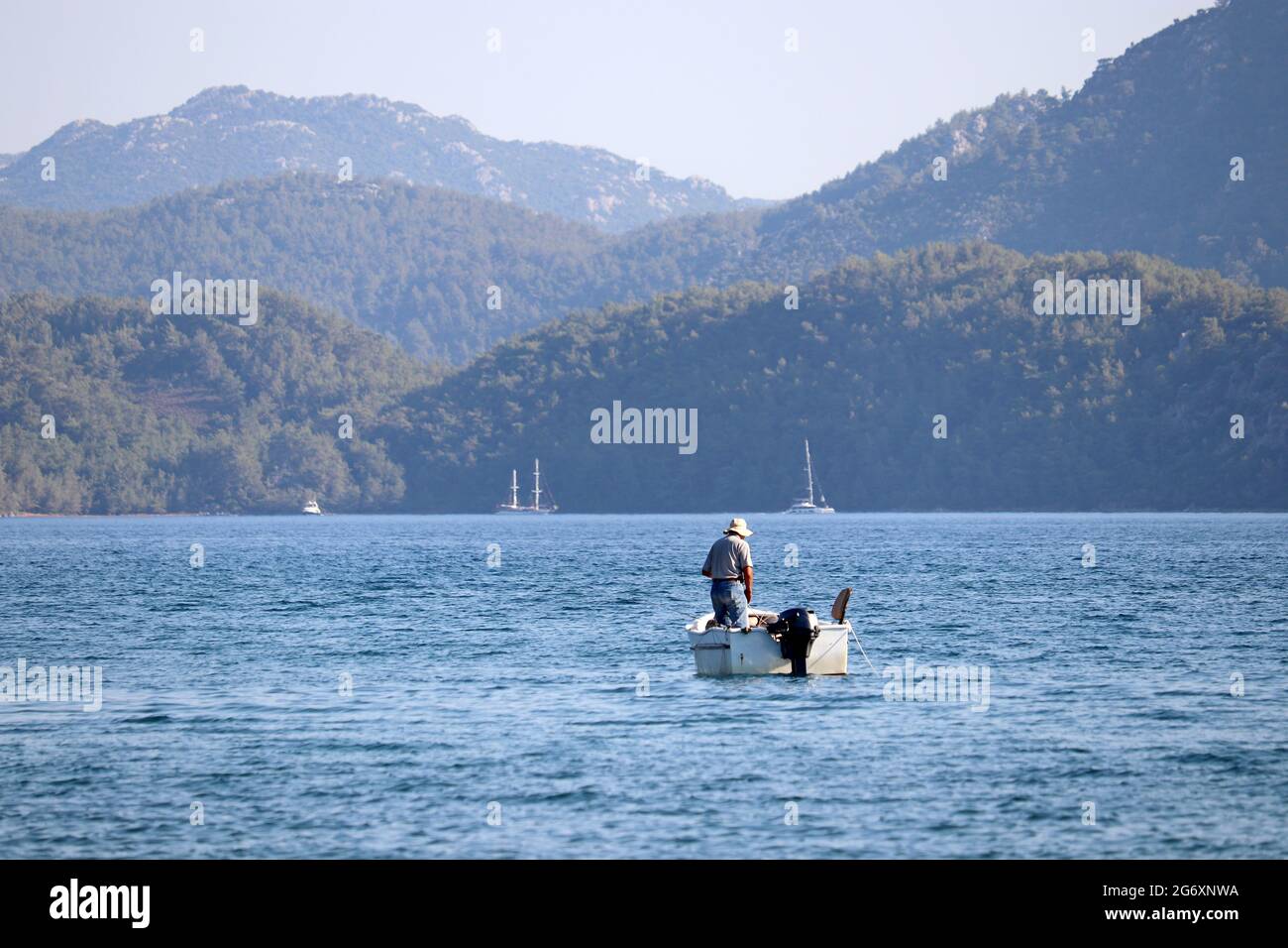 Bateau de pêche dans la mer sur fond de montagnes vertes dans la brume. Pêcheur dans une baie de la mer Égée, paysage pittoresque Banque D'Images