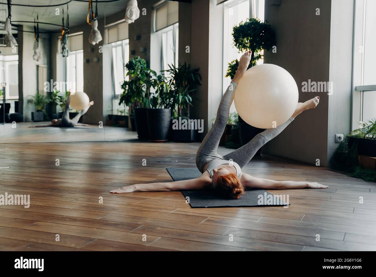 Faites de l'exercice à la femme avec un ballon d'exercice sur un tapis de yoga dans un studio de fitness Banque D'Images