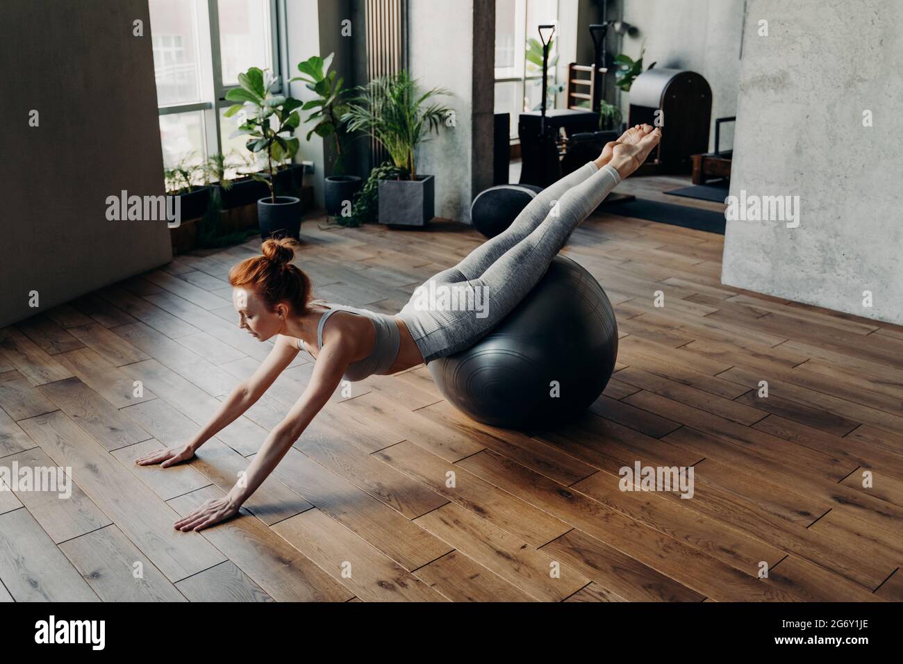 Femme mince qui s'équilibre sur le ballon d'exercice de stabilité dans le studio de fitness Banque D'Images
