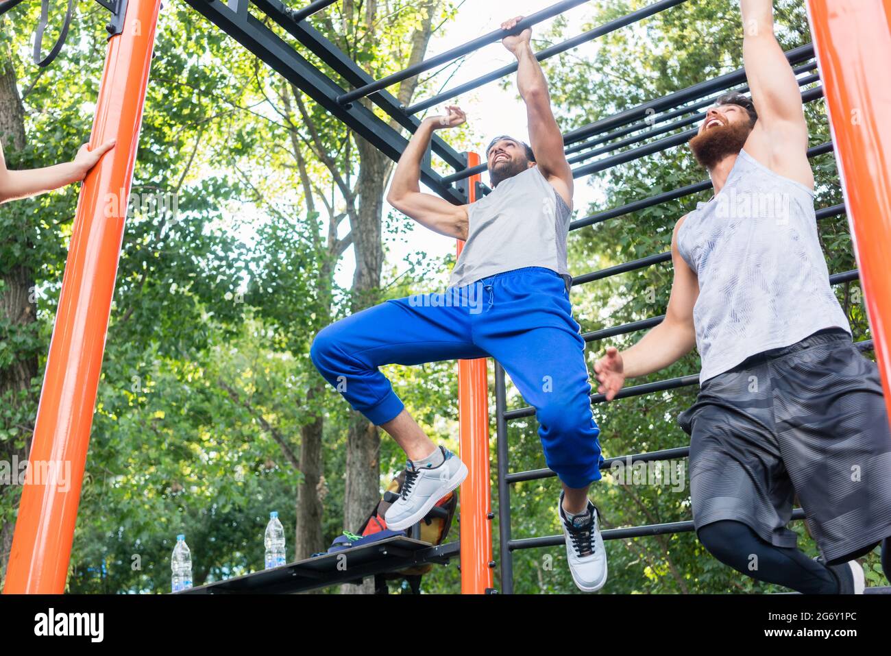 Faible angle de vue des deux hommes forte et compétitive sur l'exercice de barres pour le haut-corps dans un parc de la gymnastique moderne Banque D'Images