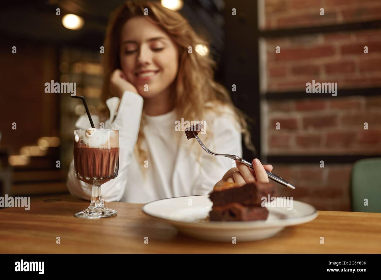 Une femme positive mangeant du gâteau et buvant du café Banque D'Images