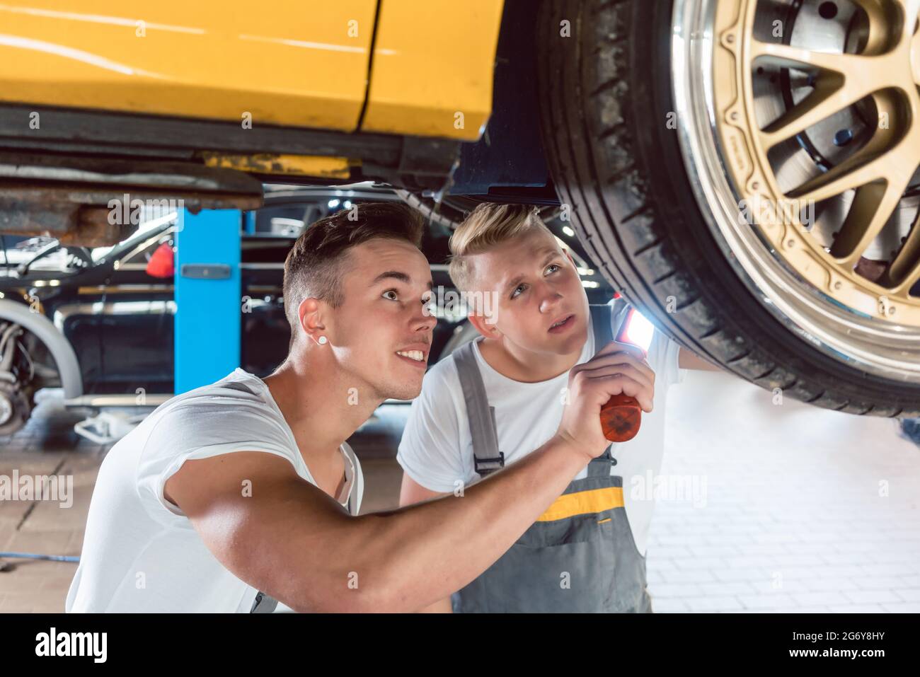 Deux mécaniciens auto tuning une voiture par la modification des jantes, tout en travaillant ensemble dans un atelier de réparation automobile moderne Banque D'Images