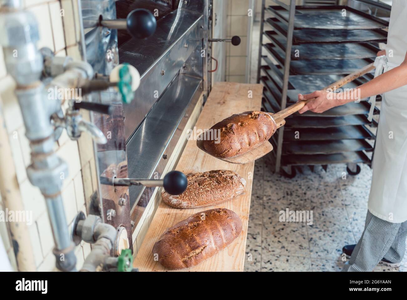 Femme de mettre du pain Boulangerie pâtisserie à bord avec pelle Banque D'Images