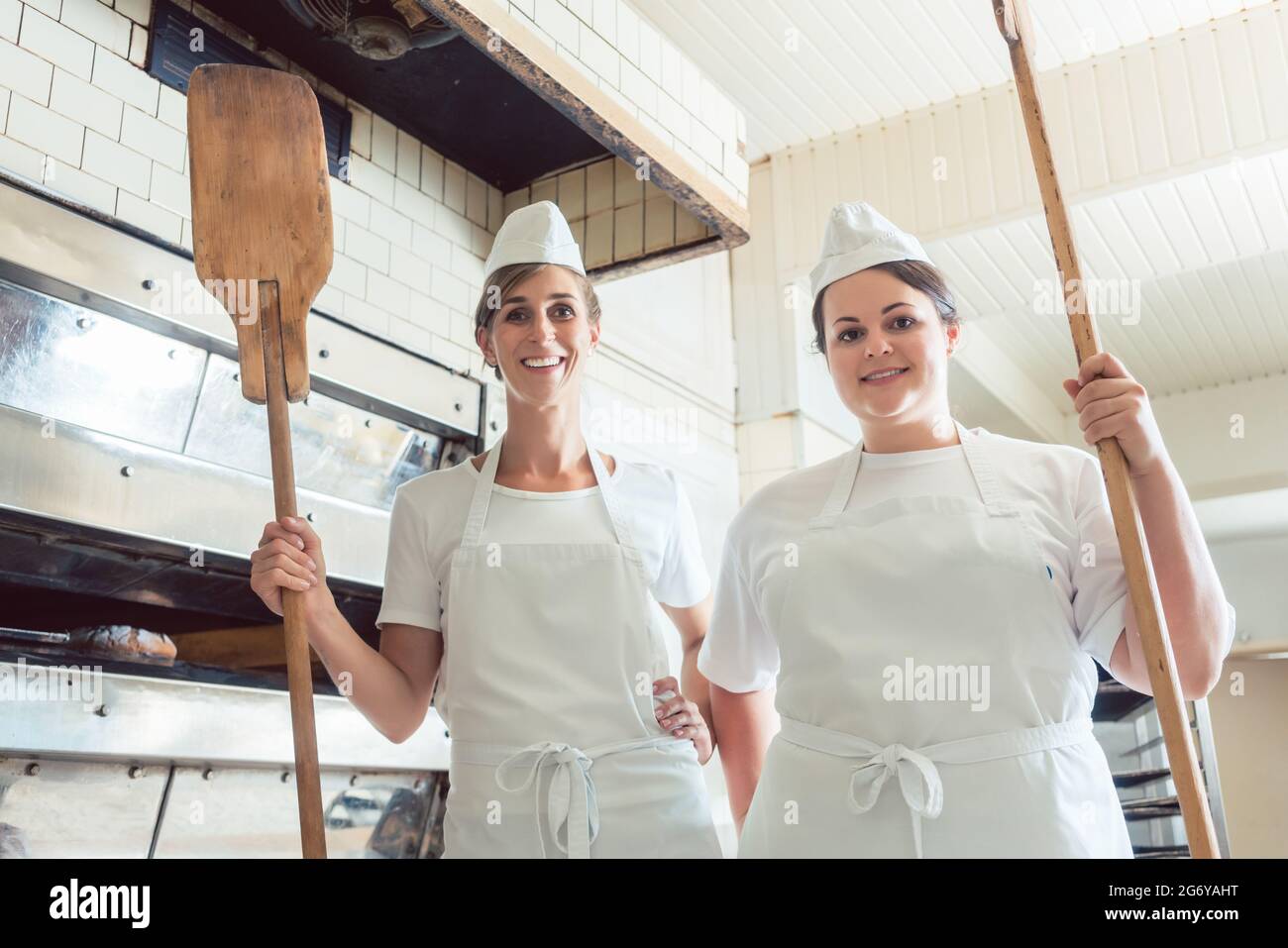 Une équipe de boulangeuses se tenant fièrement dans la boulangerie, se portant les pouces Banque D'Images