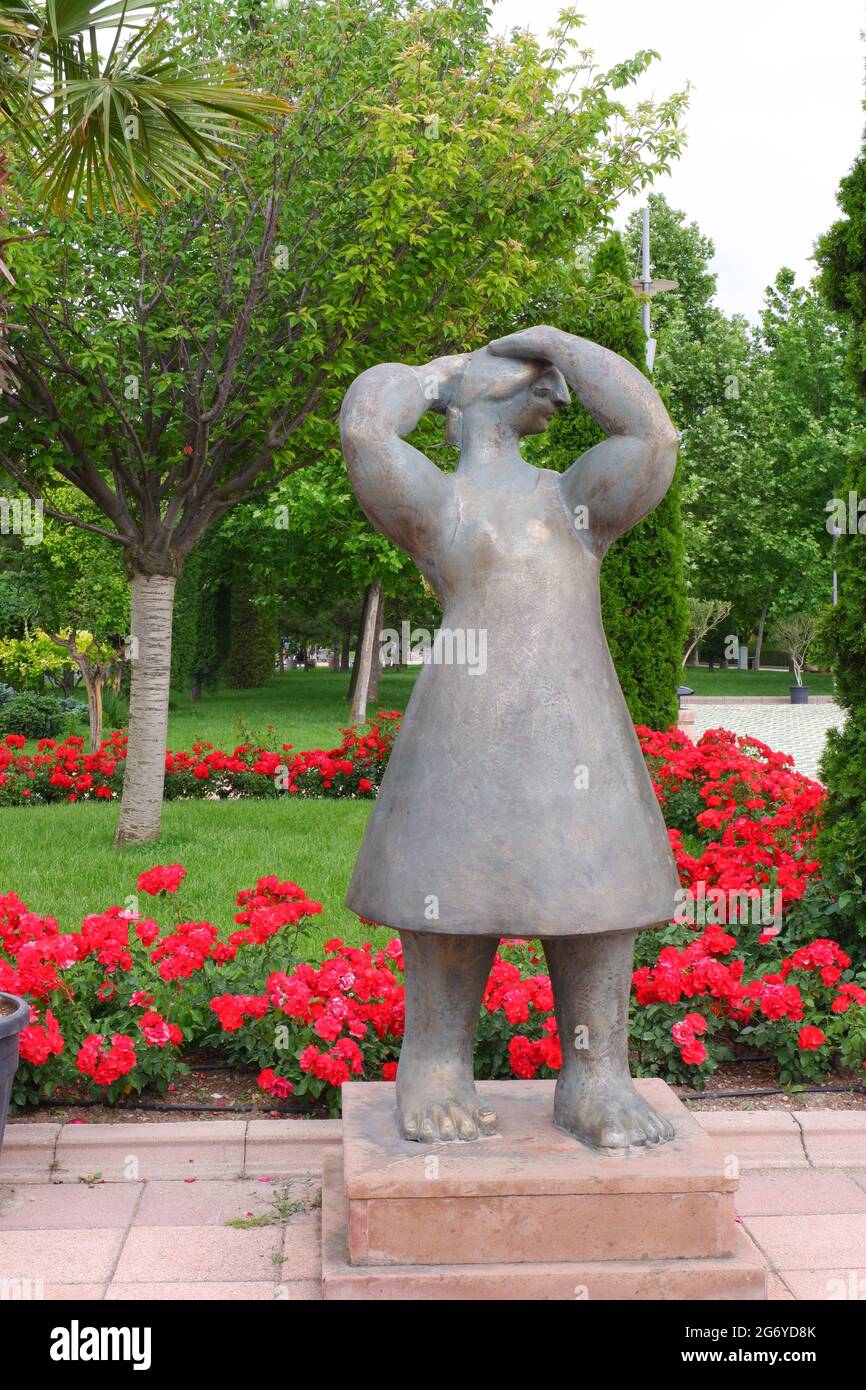 Statue de femme surréaliste avec roses et arbres à l'arrière-plan à l'extérieur au parc Banque D'Images