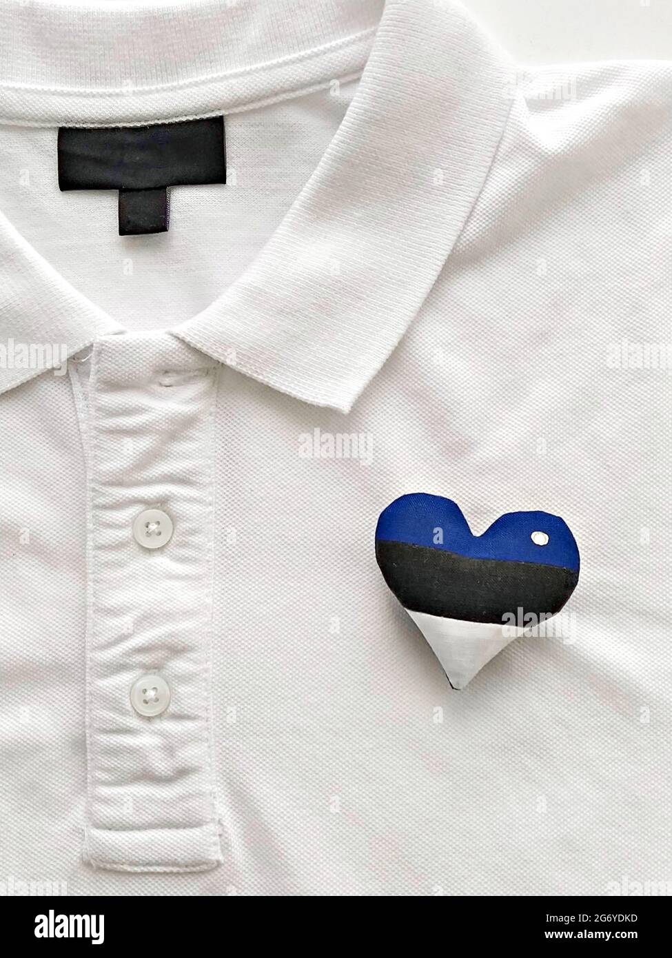 Coeur fait à la main, drapeau estonien, broche sur t-shirt blanc. Célébration de la journée de l'indépendance de l'Estonie Banque D'Images