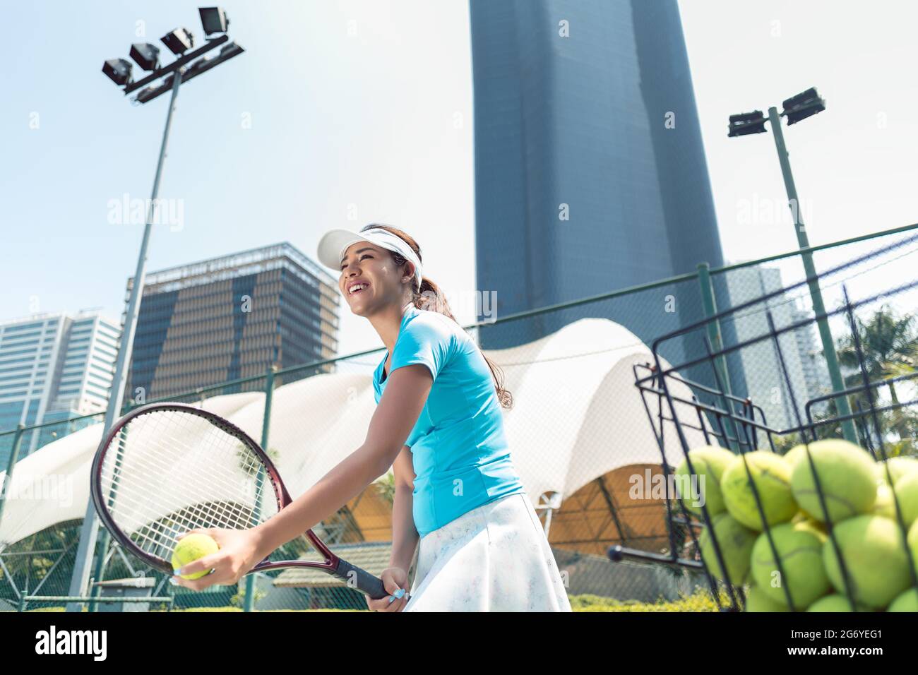 Vue en contre-plongée une belle femme prête à servir tout en jouant au tennis dans un lieu avec des équipements modernes Banque D'Images
