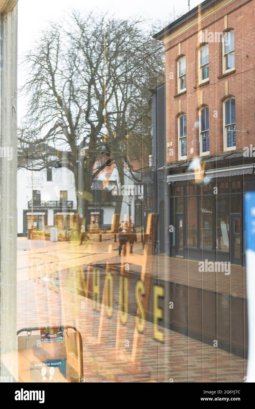 Nouvelle place de marche, montre un homme marchant sur une route parlant sur téléphone mobile, dans un reflet de fenêtre avec des couleurs acides, montre des bollards de rue. Banque D'Images