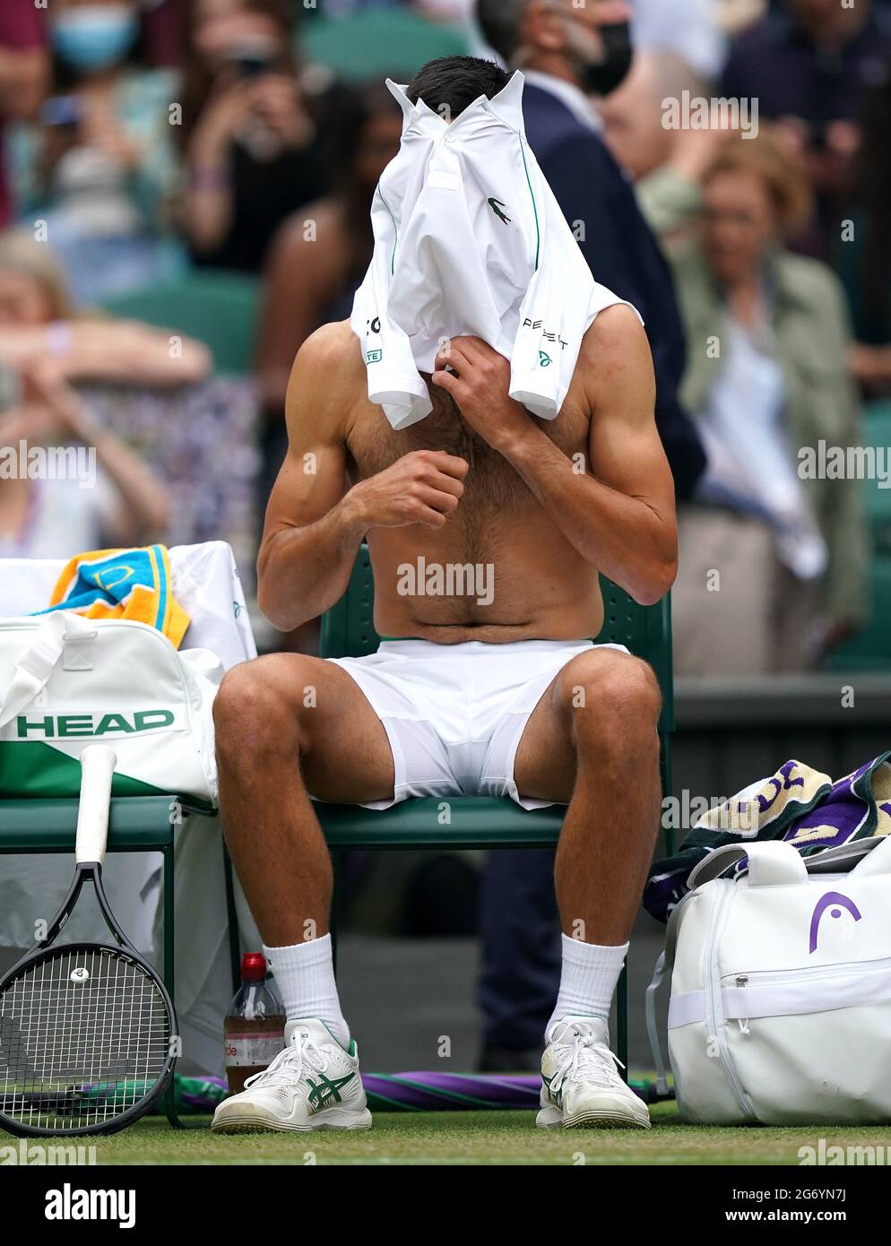 Novak Djokovic change de maillot lors d'une pause en jeu contre Denis Shapovalov lors du match de demi-finale sur le court central le 11 jour de Wimbledon au All England Lawn tennis and Croquet Club, Wimbledon. Date de la photo : vendredi 9 juillet 2021. Banque D'Images