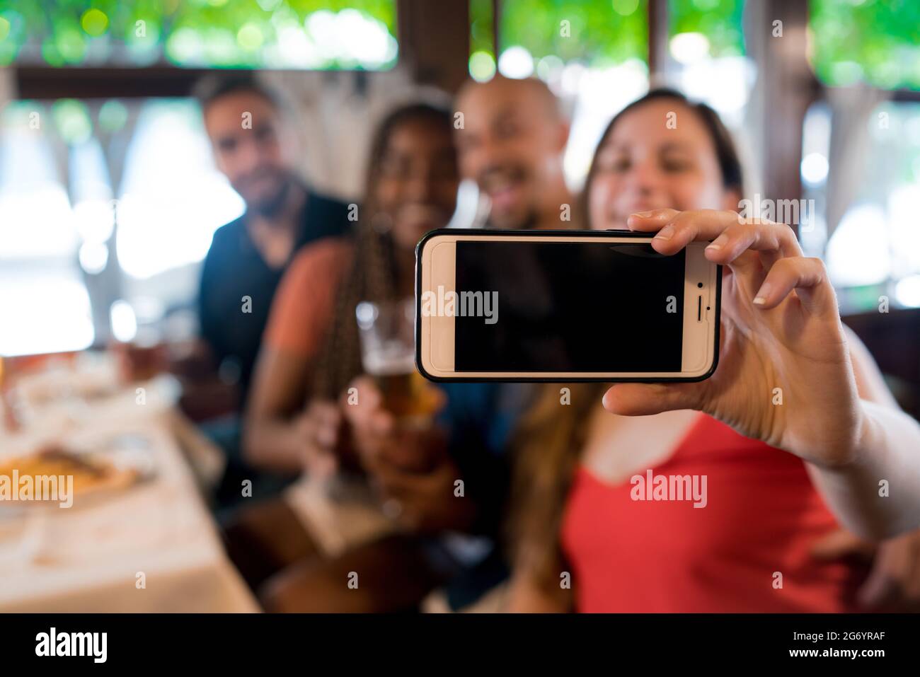 Groupe d'amis prenant un selfie avec un téléphone portable dans un bar. Banque D'Images