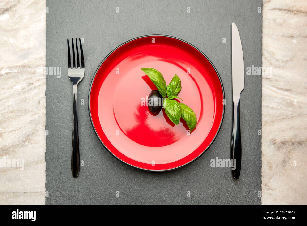 Régime alimentaire. Petite quantité d'aliments sur l'assiette. Une olive  est dans une assiette rouge, un couteau et une fourchette. Perte de poids  et concept de régime. Espace vide pour le texte Photo