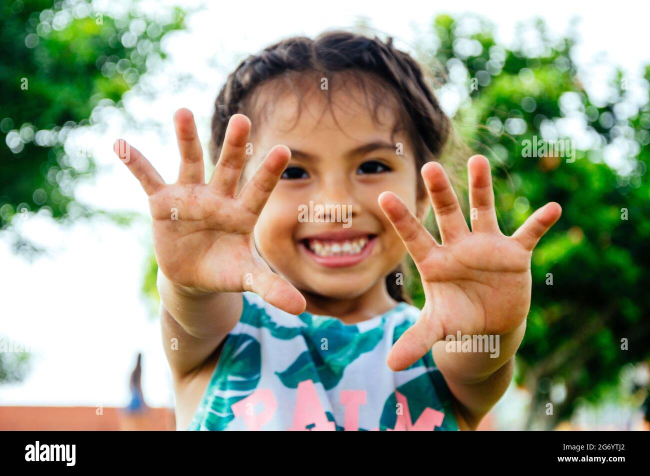 Une jeune fille de six ans au Pérou sourit et montre les paumes de ses mains écartées. Banque D'Images