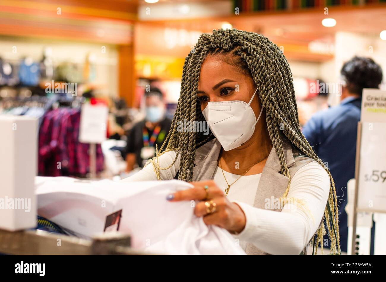 Belle femme avec des tresses et un masque de protection sur son visage antivirus. Concept de protection contre les virus dans les industries de la mode, de la beauté et du shopping. Banque D'Images