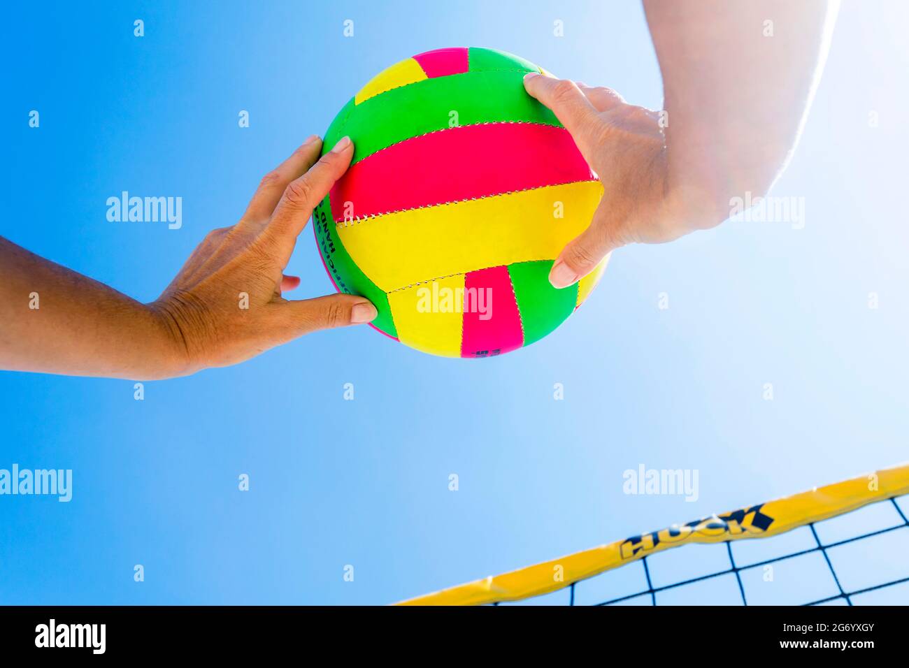 mains recevant le ballon de beach-volley de couleur volante Banque D'Images